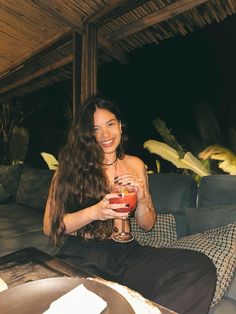 a woman sitting on a couch holding a drink