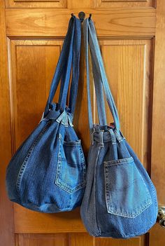 two denim purses hanging on a wooden door