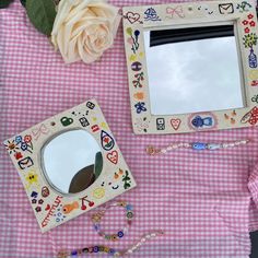 a pink table topped with a mirror and other items next to a flower on top of a checkered cloth