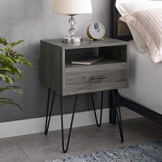 a nightstand with a lamp on top of it next to a bed in a bedroom