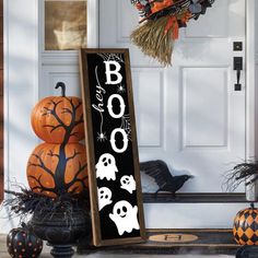 a sign that says boo on it in front of a door with pumpkins and other decorations