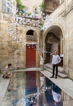 two people are standing in front of a pool with water and flowers floating from it