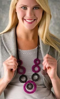 a woman is smiling and holding onto a necklace that has two circles on the front