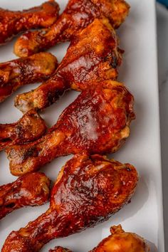 chicken wings covered in bbq sauce sitting on a white platter, ready to be eaten