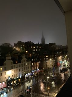 the city is lit up at night and it's raining