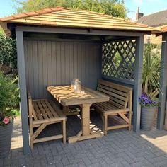 a wooden table and benches under a gazebo