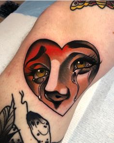 a woman's arm with a heart and face tattoo on the left side of her leg