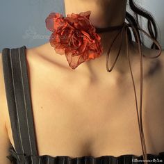 a woman wearing a red flower on her neck