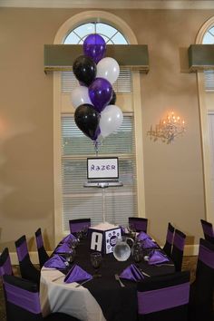 the table is set with purple and black balloons