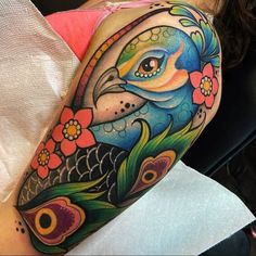 a woman's arm with a colorful tattoo design on her left shoulder and an image of a fish in the background