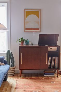 a living room with a blue couch and a wooden cabinet in front of a window