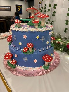 a three tiered blue cake with mushrooms on the top is sitting on a table