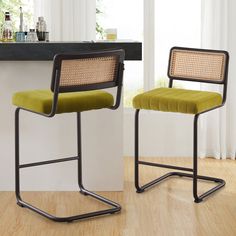 two chairs with green upholstered cushions sit in front of a counter and window