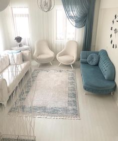 a living room filled with white furniture and blue accents on the walls next to a window