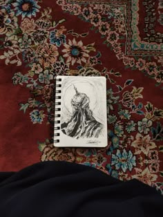 a notebook with an image of a man on it sitting on a bed next to a rug