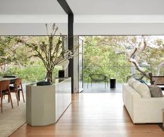 a living room filled with furniture next to a large glass window covered in lots of trees