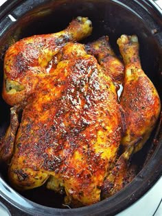 a close up of a cooked chicken in a crock pot on top of a stove