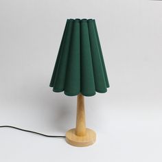 a green lamp with a wooden base on a white background