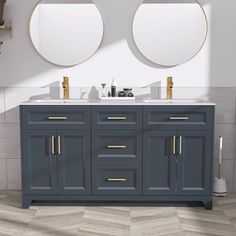 two round mirrors are above the double sink vanity in this white and gray bathroom with wood flooring