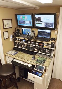 there is a desk with multiple computers and other electronic equipment on it in the room