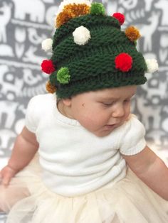 a baby wearing a knitted christmas tree hat