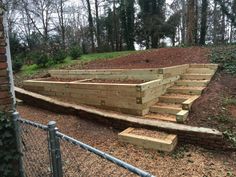 some wooden steps on the side of a hill next to a brick wall and fence