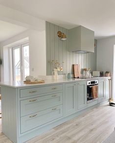 a kitchen with light blue cabinets and white counter tops, gold pulls on the cupboards