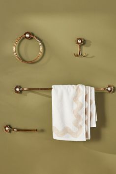 a bathroom with gold fixtures and towels hanging on the wall next to toilet paper rolls