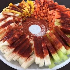 a platter filled with cut up vegetables on top of a white plate and sauce in the center