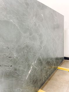 a grey marble wall with yellow lines on the floor