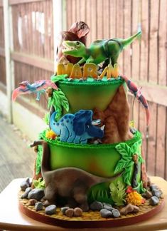 a three tiered cake is decorated with dinosaurs and other animal figurines on it