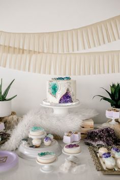 a table topped with cakes and cupcakes next to succulents on plates