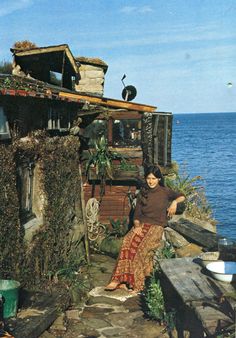 a woman sitting on the edge of a house next to the ocean