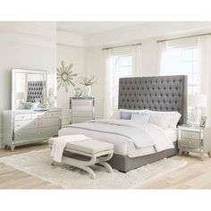 a bedroom scene with focus on the bed, dressers and mirror cabinetry in the background