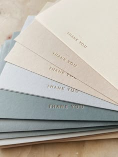 several folded thank cards with the words thank you written on them in gold, silver, and blue