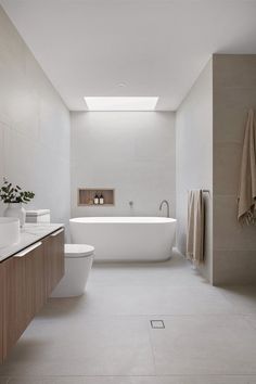 a bathroom with a white bath tub sitting next to a toilet under a skylight