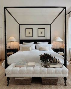 a bedroom with a four poster bed and white linens on the headboard, footstools, lamps, and two nightstands