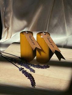 two yellow vases sitting on top of a wooden cutting board next to lavender flowers