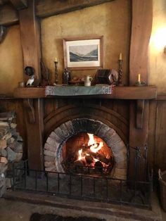 a fireplace with logs in it and a painting on the wall above it that says, this is an old fashioned fire place