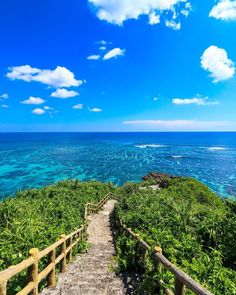 stairs leading down to the ocean on a sunny day with blue sky and white clouds