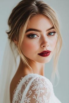 a woman with red lipstick wearing a wedding dress and veil on her head, looking off to the side