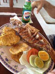 a plate with fish, chips and vegetables on it next to a bottle of beer