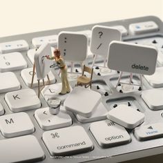 a computer keyboard with miniature figurines sitting on it