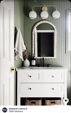 a bathroom with green walls and white furniture in front of a mirror on the wall