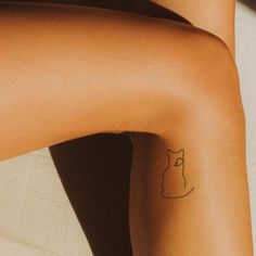 a woman's legs with a cat tattoo on her left leg and right leg