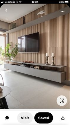 a living room with a large tv on the wall and some plants in front of it