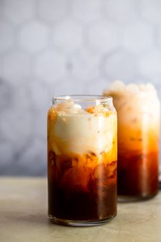 two glasses filled with iced coffee sitting on top of a table