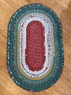 a red and green oval rug sitting on top of a wooden floor