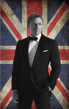 a man in a tuxedo with the british flag behind him