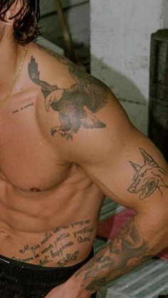 a man with tattoos on his chest holding a cell phone